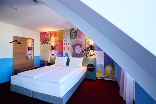 莱比锡莱比锡麦克梦想酒店的卧室设有白色大床和色彩缤纷的墙壁。