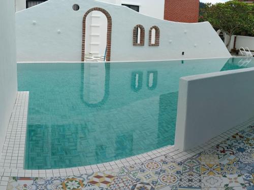 怡保Ipoh Santorini Hideaway - Hotel Inspired的一座铺有瓷砖地板的游泳池和一座建筑