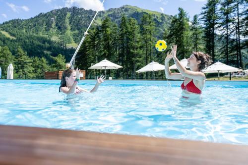 蒙热内夫尔Villages Clubs du Soleil - MONTGENEVRE的两个女人在游泳池玩球