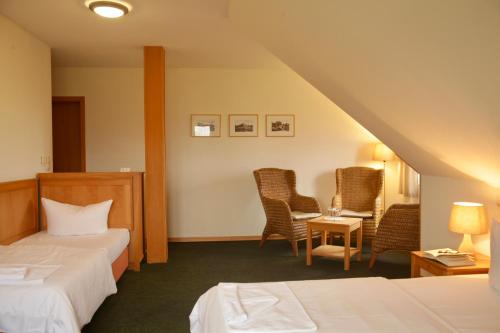 克洛斯特Hotel Enddorn Hiddensee的酒店客房带两张床和一张桌子以及椅子。