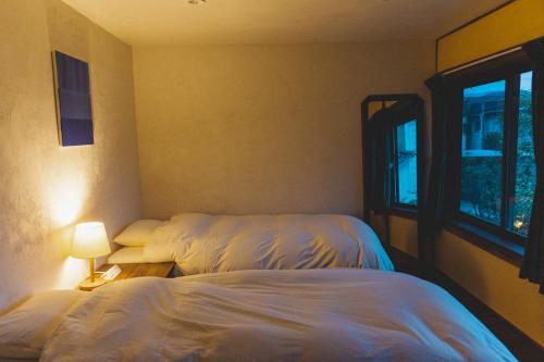 SetoMasukichi 古民家宿ますきち 駐車場無料的一间卧室设有两张床和窗户。