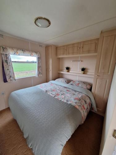 BurumStacaravan Elly, Minicamping de Grutte Earen的卧室配有一张大白色床和窗户