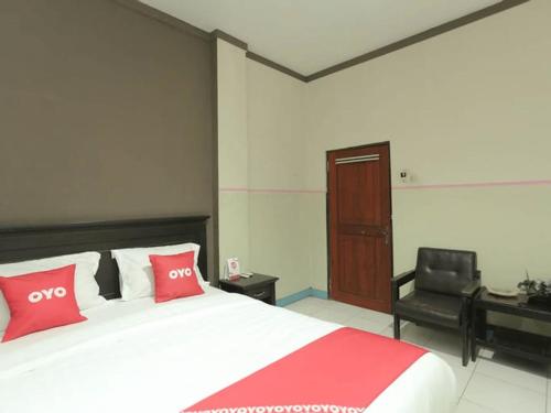 贝努阿亚尔Hotel Kharisma的一间卧室配有一张带红色枕头的床和一张书桌