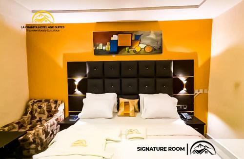 Ado EkitiLA GRANITA HOTEL AND SUITES的一间卧室配有一张带橙色墙壁的大床