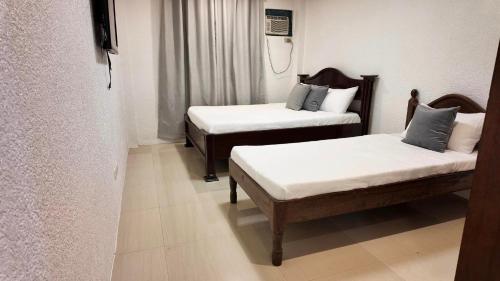 公主港CECILIAS INN的一间设有两张带白色床单的床的房间