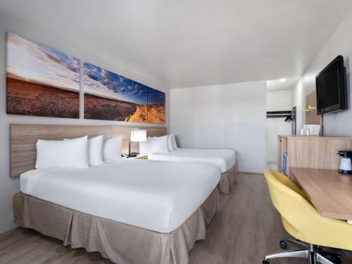 拉斯维加斯Days Inn by Wyndham Las Vegas Airport Near the Strip的酒店客房配有两张床和一张书桌