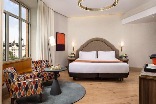 马德里马德里普拉多大道NH精品酒店的配有一张床和一把椅子的酒店客房