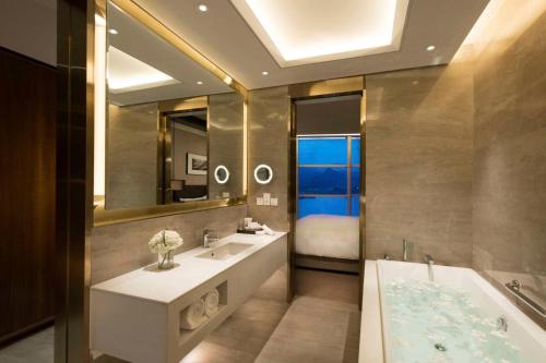 怀柔北京日出东方凯宾斯基酒店的一间带两个盥洗盆、一个浴缸和一张床的浴室