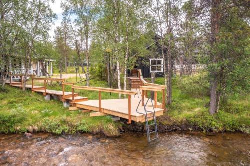 萨利色尔卡Wilderness Hotel Muotka & Igloos的一条木桥,横跨树木的河流