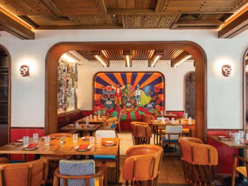 曼谷诺富特生活曼谷素坤逸传承的一间带木桌和椅子的餐厅以及壁画