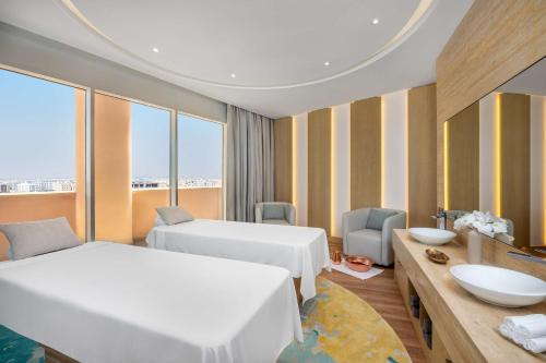 阿可贺巴Hilton Al Khobar King Fahd Causeway的酒店客房设有两张床和一张带水槽的书桌。