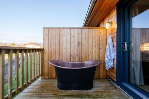 莱斯比Laceby Manor - Spa & Golf Resort的浴缸位于围栏旁边的甲板上