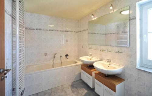 富伦多夫Stunning Apartment In Fuhlendorf With Lake View的浴室配有两个盥洗盆、浴缸和浴缸。
