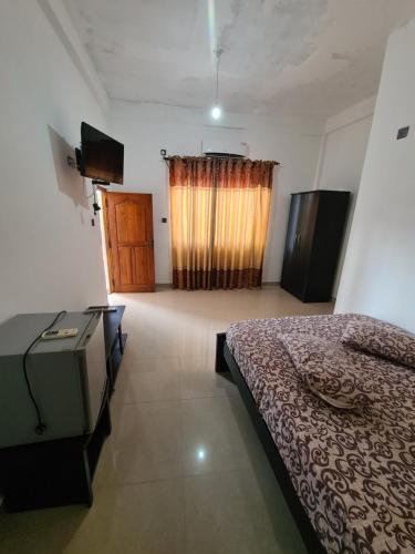 AmbanpolaHotel Mihira Village的一间卧室配有一张床、一台电视和一个窗口