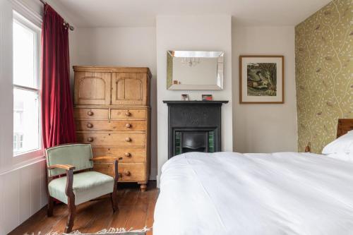 布莱顿霍夫GuestReady - Magic Lantern House - Close to Beach的一间卧室配有一张床、一把椅子和一个壁炉