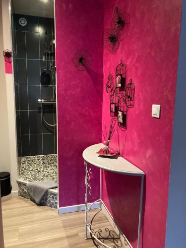 莱瓦尔坦Au Domaine de PY的浴室设有粉红色的墙壁、桌子和淋浴