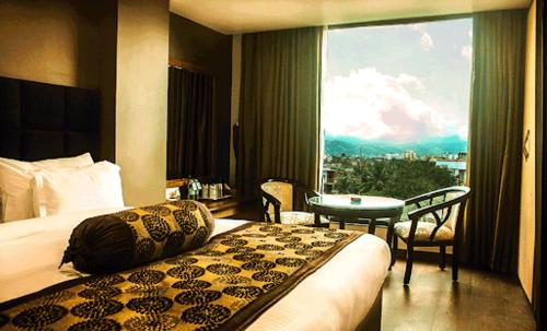古瓦哈提HOTEL SHOOLIN GRAND的酒店客房设有床、桌子和窗户。