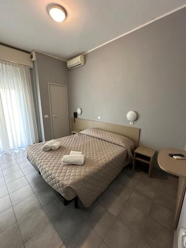 里米尼奥地利酒店的一间卧室配有一张床,上面有两条毛巾