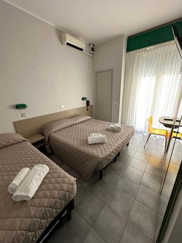 里米尼奥地利酒店的酒店客房设有两张床、一张桌子和一个窗户。