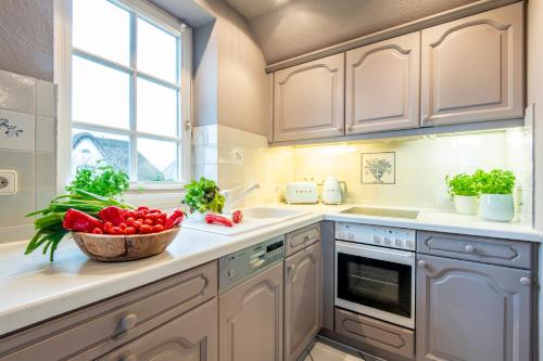 摩尔苏姆Heefwai 2 W6的厨房配有白色橱柜和一碗西红柿