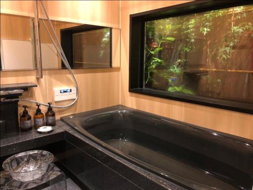 京都Kamozen Kyoto Machiya Stay的一个带水族箱的浴室内的大型黑色浴缸