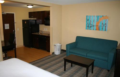 杰克逊维尔MainStay Suites Jacksonville near Camp Lejeune的一间带蓝色沙发的客厅和一间厨房