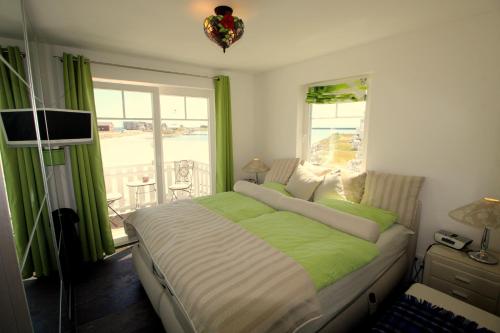 卡珀尔恩Strandhaus Libelle - direkt am Strand der Ostsee的卧室设有绿色和白色的床和窗户。
