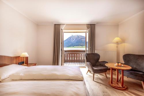 圣沃尔夫冈Hotel Weisser Hirsch的酒店的客房 - 带一张床、椅子和窗户
