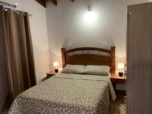 LuqueHermosa casa, zona Aeropuerto的一间卧室配有一张床,两盏台灯放在两张桌子上