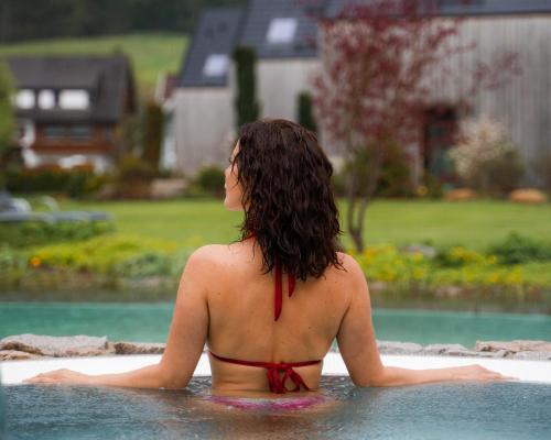 拜尔斯布龙Wellness & Genuss Resort - Engel Obertal的坐在游泳池里的比基尼女人