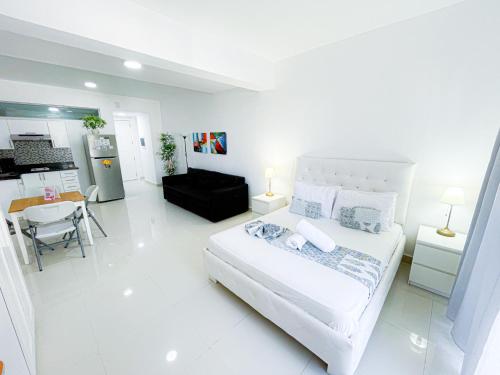 蓬塔卡纳DUKASSI SUITES Hotel ROOMS BEACH Bavaro WIFI Parking ROOFTOP POOL & SPA的一间白色卧室,配有床和厨房