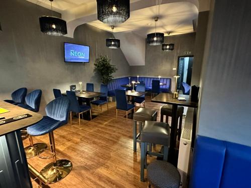布莱克浦Hotel Neon的餐厅设有蓝色的桌椅和电视。