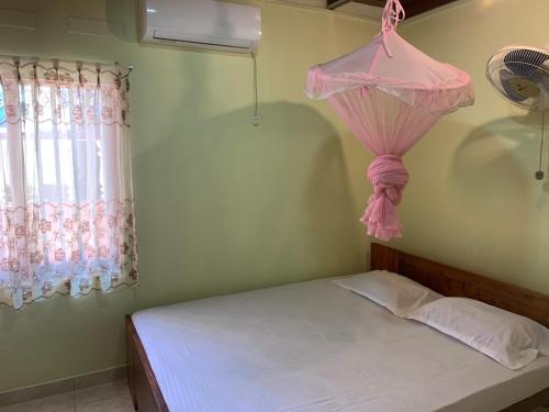 安伯朗戈德Cinnamon Villa AMBA的一间卧室配有一张带粉红色窗帘的床