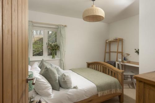 Saint MawganLobbs Cottage, St Mawgan的卧室配有带白色枕头的床和窗户。