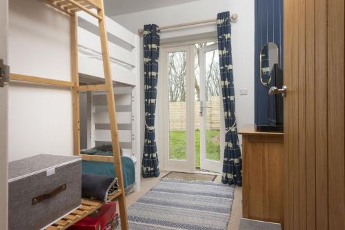 Saint MawganLobbs Cottage, St Mawgan的一间卧室配有双层床和窗户。