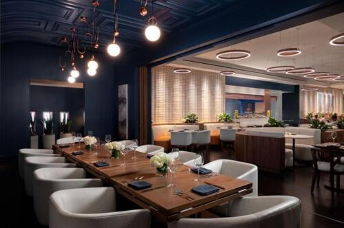 波士顿Mandarin Oriental, Boston的一间带长桌和白色椅子的用餐室