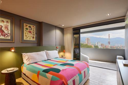 麦德林Versus Hotel的一间卧室设有一张色彩缤纷的床和一个大窗户