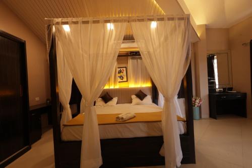 罗纳瓦拉Lavender Heights的卧室配有带白色窗帘的天蓬床
