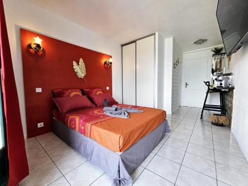 莱特鲁瓦西莱Sweet Crépuscule - Studio avec Vue Mer Imprenable & Piscine的一间卧室配有一张红色墙壁的床