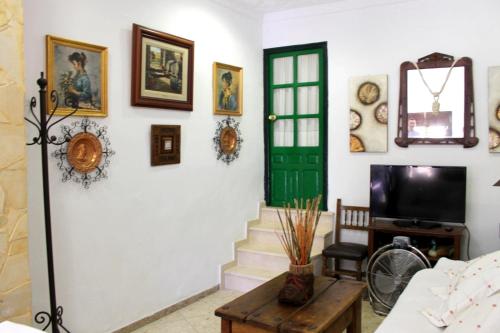 隆达Typical Andalusian house in the center of Ronda / Casa típica andaluza en el centro de Ronda.的客厅设有绿门,墙上挂有图片