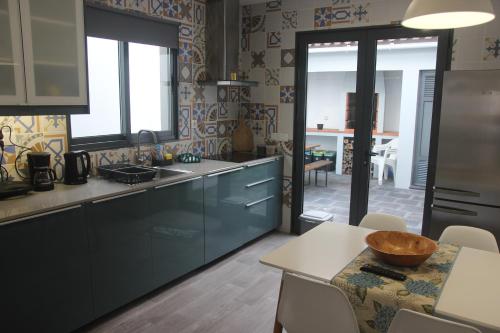 蓬塔德尔加达Casa D'Alegria的厨房配有蓝色橱柜和碗桌
