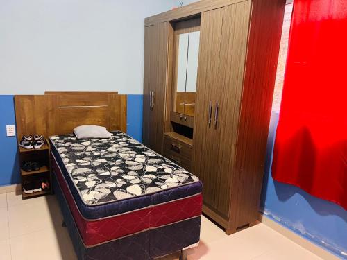 帕林廷斯Suite em Parintins的一间卧室配有一张床和一个木制橱柜