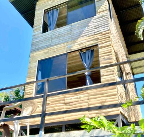 San PedrilloCotinga Nest - King Bed, Ocean View的带阳台的木制房屋,配有蓝色窗帘