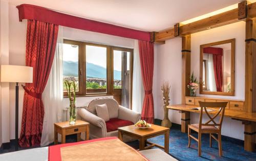 班斯科Kempinski Hotel Grand Arena Bansko的酒店客房带一张床、一张桌子和椅子