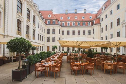德累斯顿塔森博格帕莱凯宾斯基酒店的室外餐厅设有桌椅和遮阳伞。