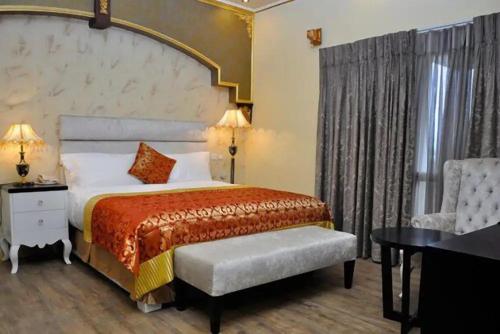 阿布贾Sandralia Hotel的一间卧室配有一张大床和一把椅子