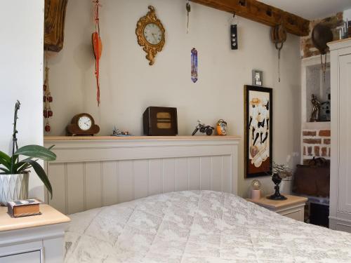LangleyBramley Cottage的卧室配有床和墙上的时钟