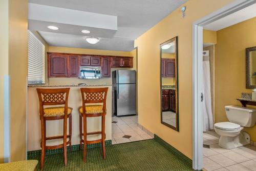 克利尔沃特Holiday Inn & Suites Clearwater Beach, an IHG Hotel的厨房配有两把椅子和冰箱