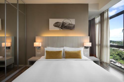 古晋古晉馨乐庭酒店的卧室配有一张带黄色枕头的大型白色床。