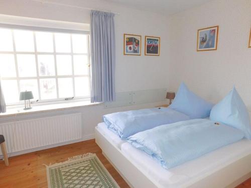 兰图姆Haus Hoppel - FeWo ground floor的一间卧室配有一张带蓝色床单的床和一扇窗户。
